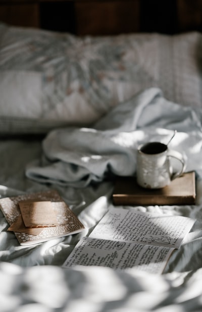 咖啡杯放在白色毯子旁边的棕色木杯垫上